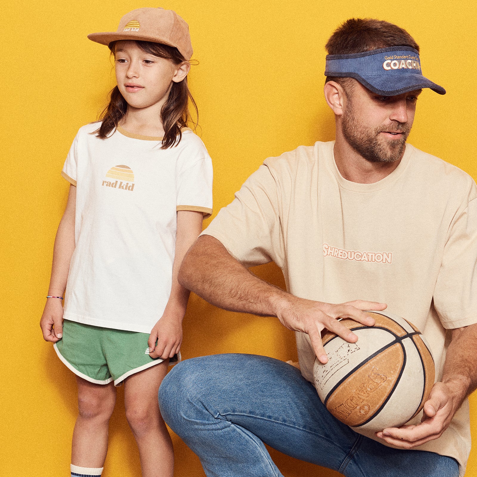 Man and young child wearing branded t-shirts against a yellow background