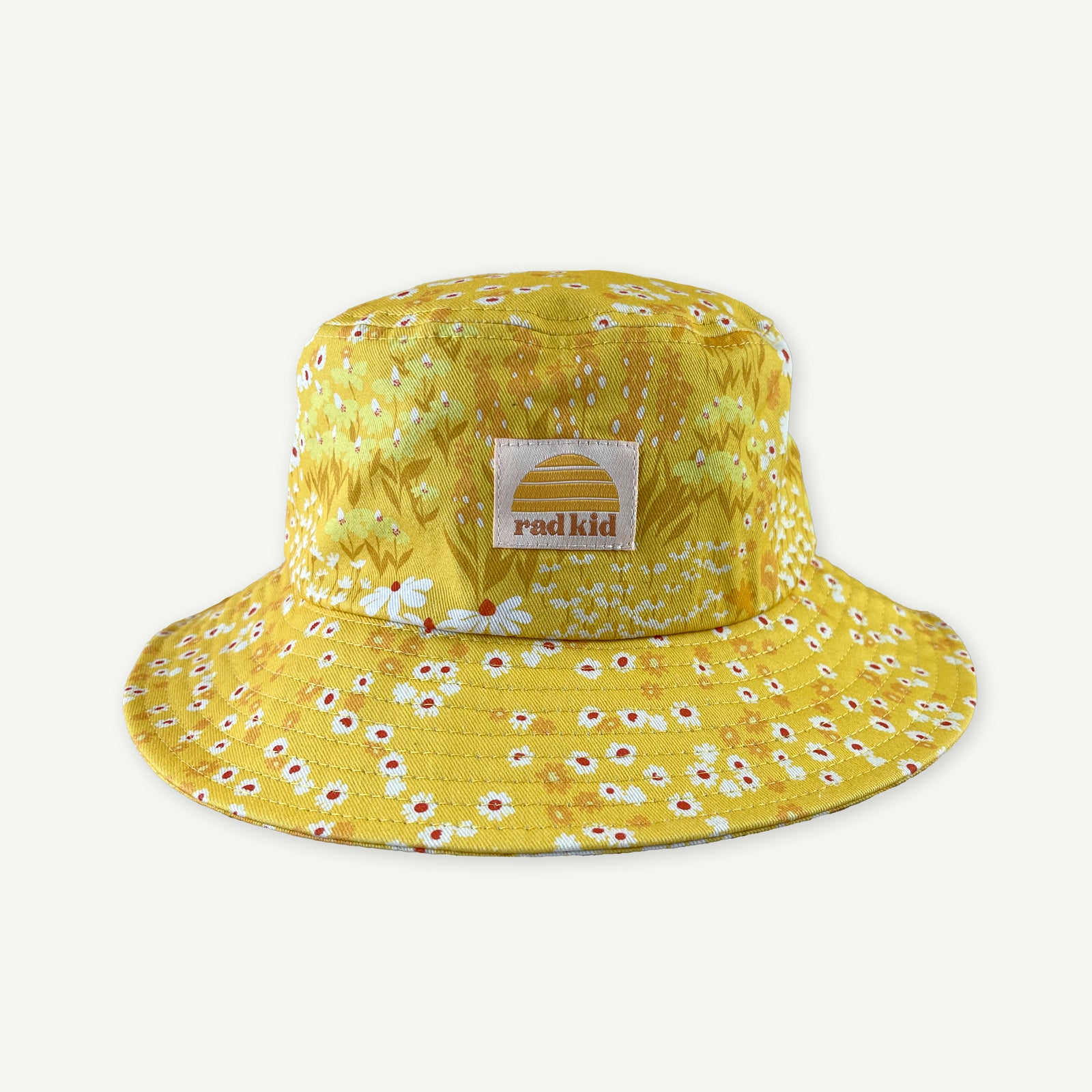 Bucket hat in a yellow Buttercup meadow of flowers print with Rad Kid patch in off white with Banabae sun Logo in Yellow sewn to Centre front.