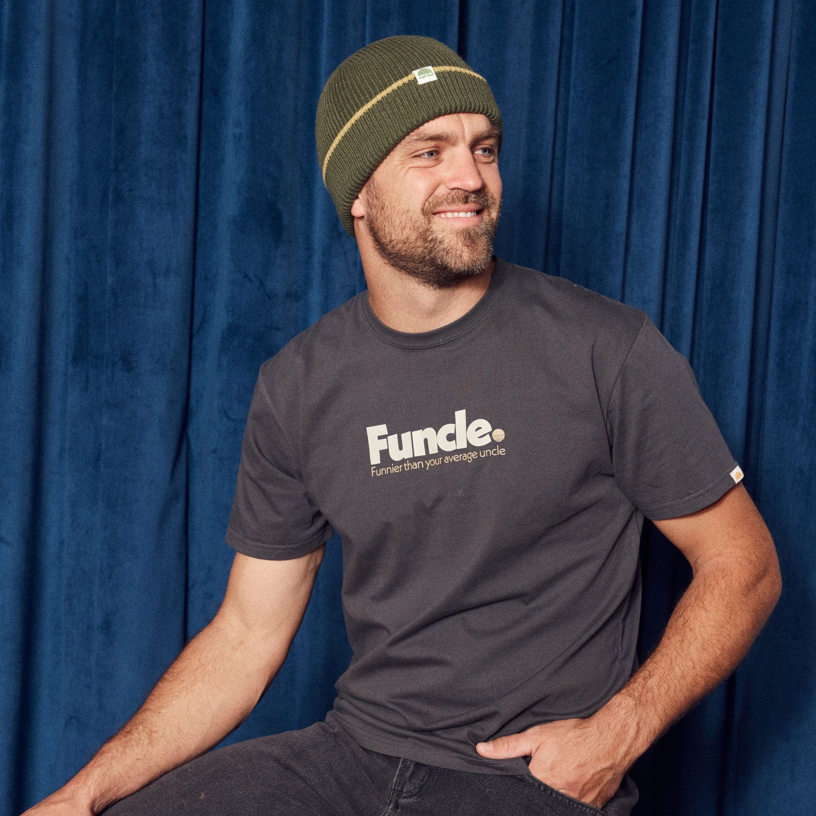 Man wearing a washed black t-shirt with 'Funcle' logo and a green beanie