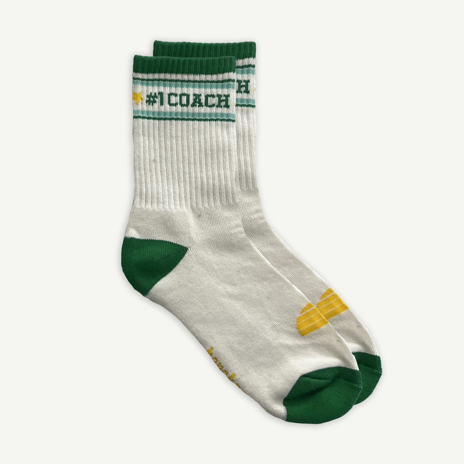 One pair of White crew socks with #1 coach in Green written horizontally, bordered with a green and aqua stripe. Toe and heal pads in contrast green with Banabae written along the sole in yellow, and the iconic Banabae sun logo in yellow placed on top of the foot when worn.