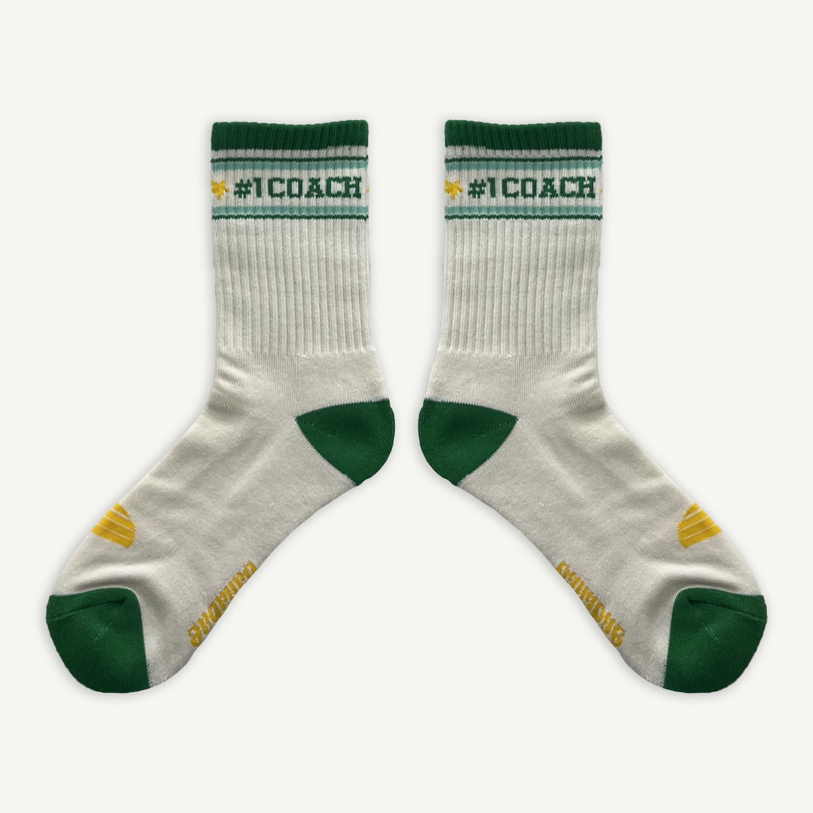 #1 Coach socks, White crew socks with #1 coach in Green written horizontally, bordered with a green and aqua stripe. Toe and heal pads in contrast green with Banabae written along the sole in yellow, and the iconic Banabae sun logo in yellow placed on top of the foot when worn.