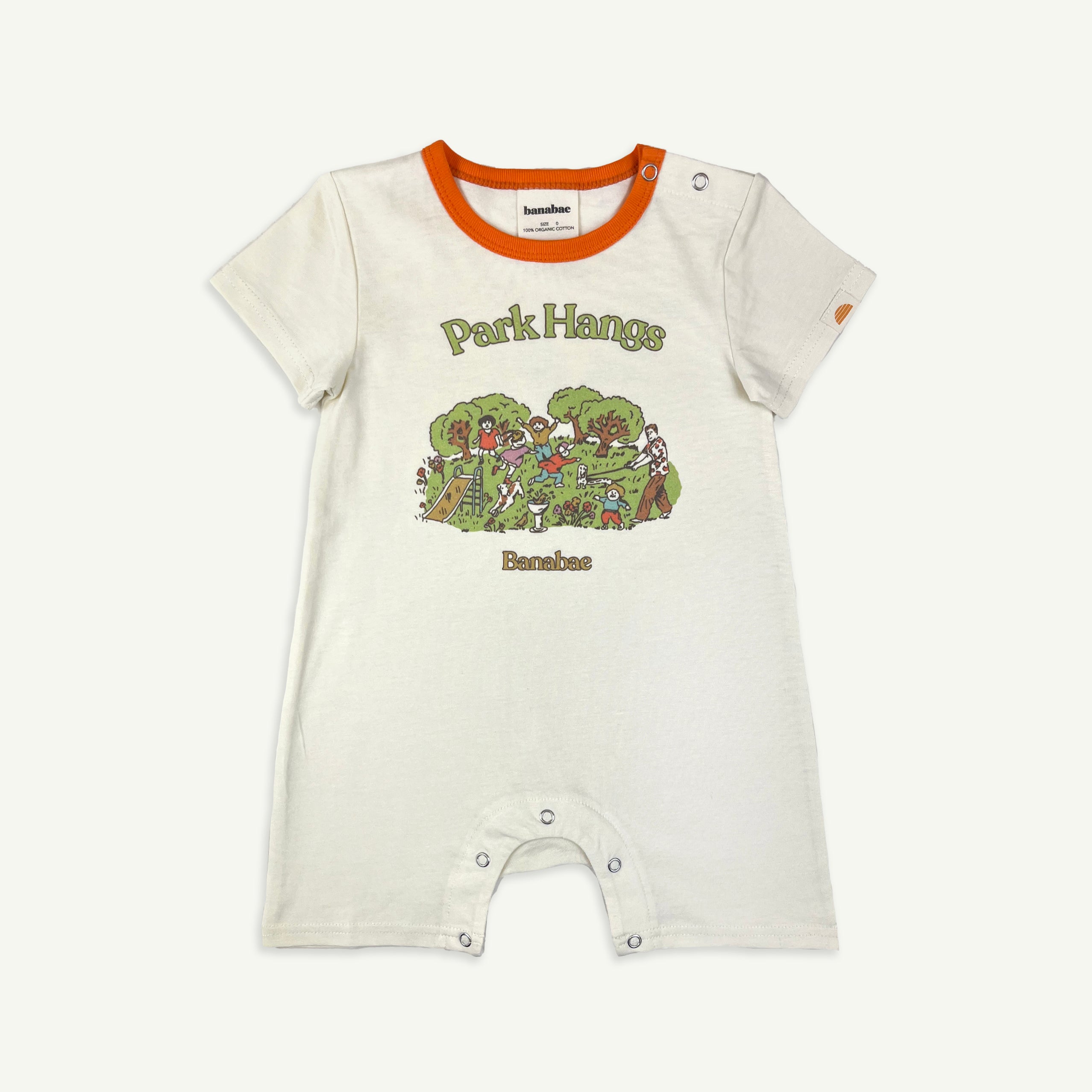 A white organic cotton playsuit for babies with 'Park Hangs' text and a park scene printed on the front, featuring orange trim.