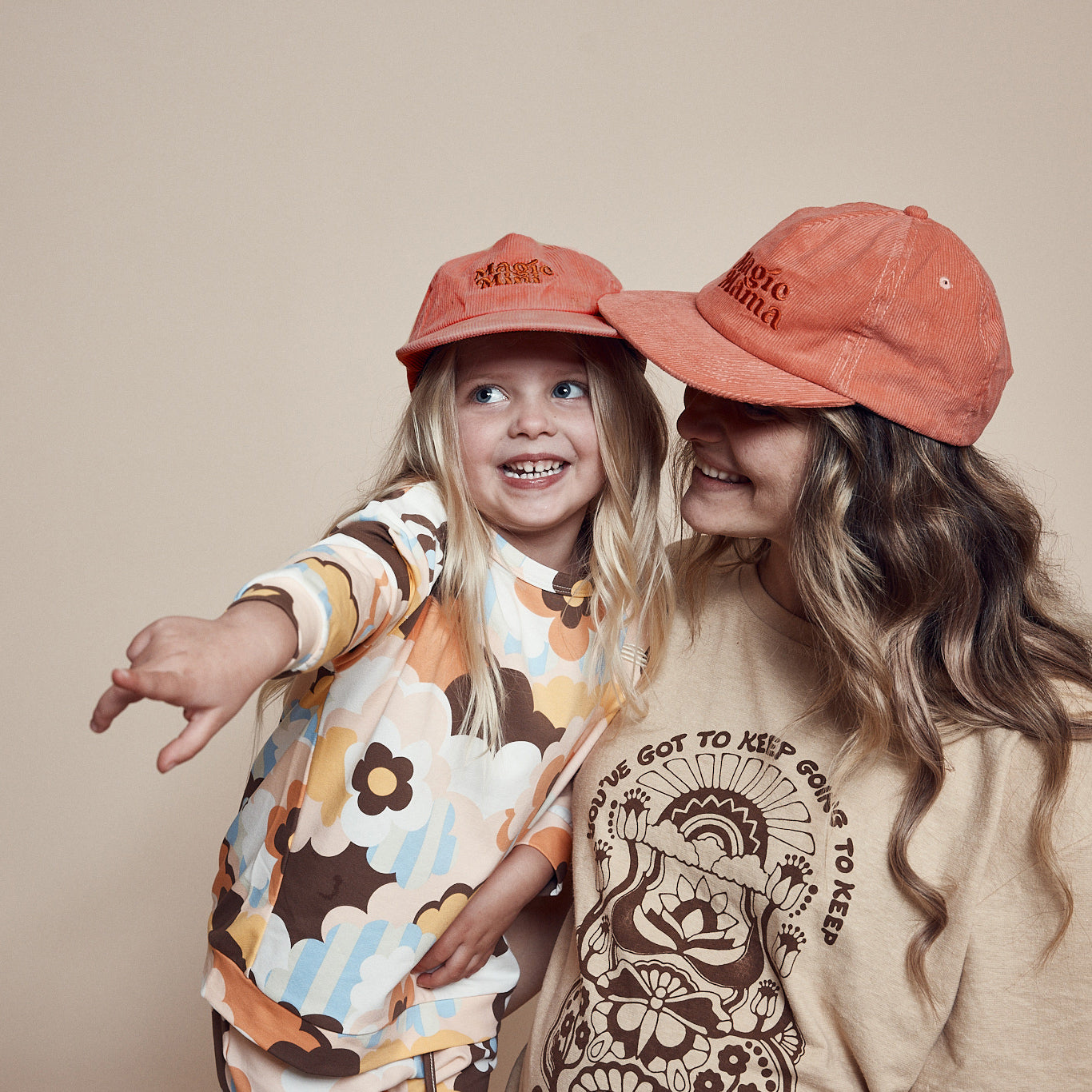 Mother and daughter wearing coordinating Magic Mini Corduroy cap and Magic Mama corduroy cap. Both are pink with embroidery on center front in darker tone of pink.