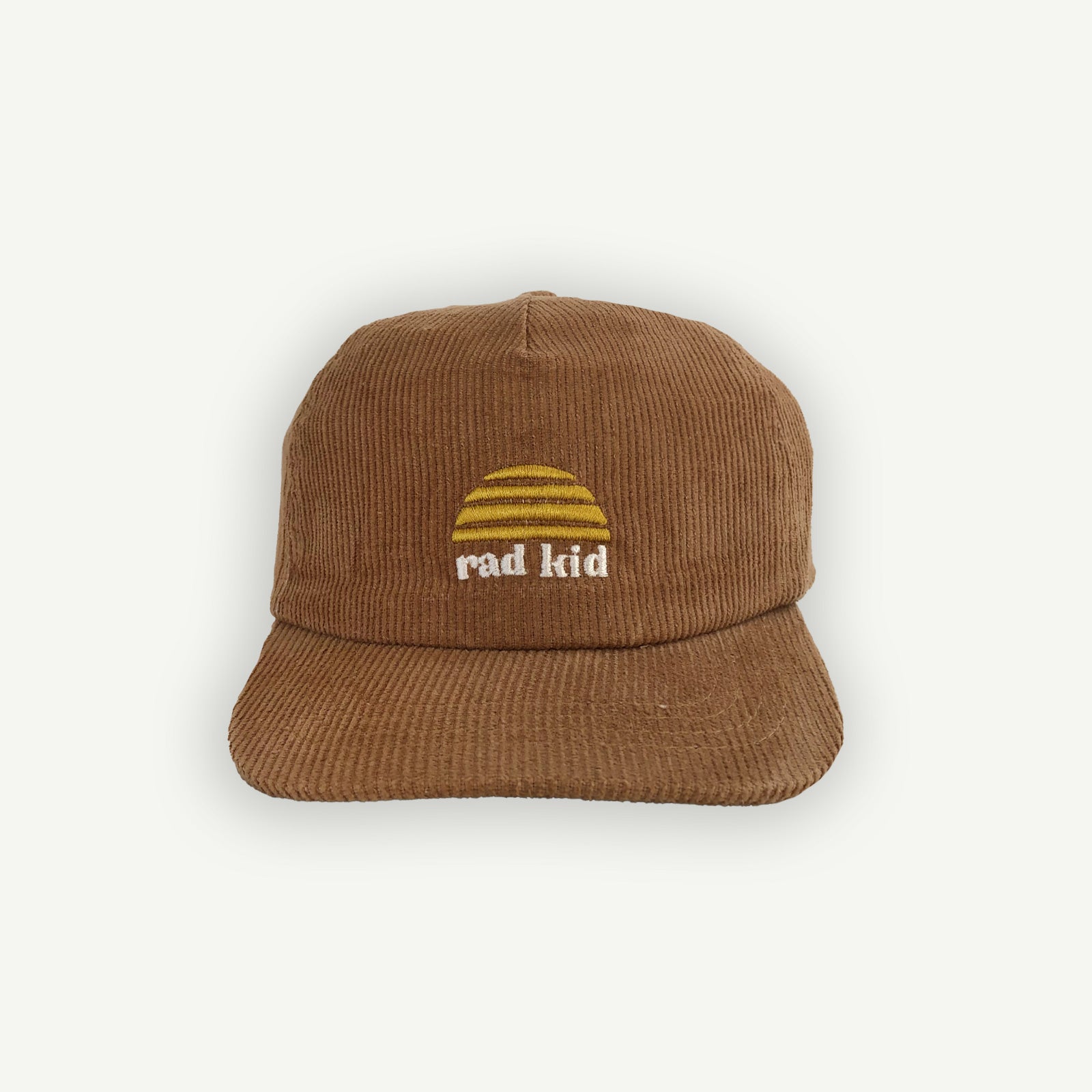 A tan brown corduroy cap with the text 'rad kid' embroidered on the front, featuring a yellow logo