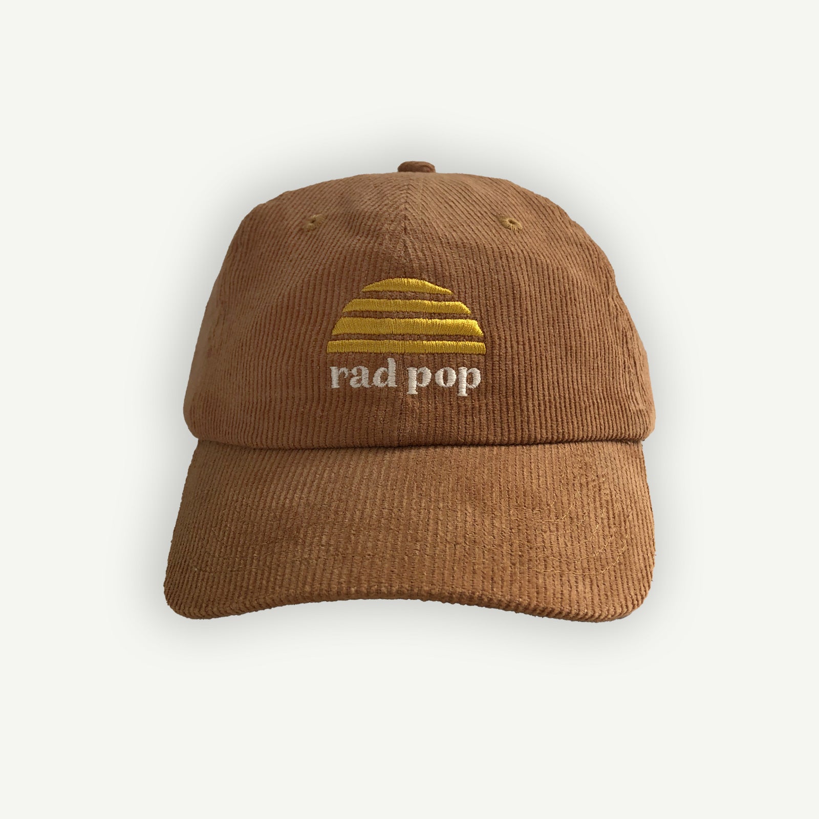 Rad pop corduroy flat peaked cap with Banabae sun logo in yellow embroidered on center front with Rad Pop underneath in off white.