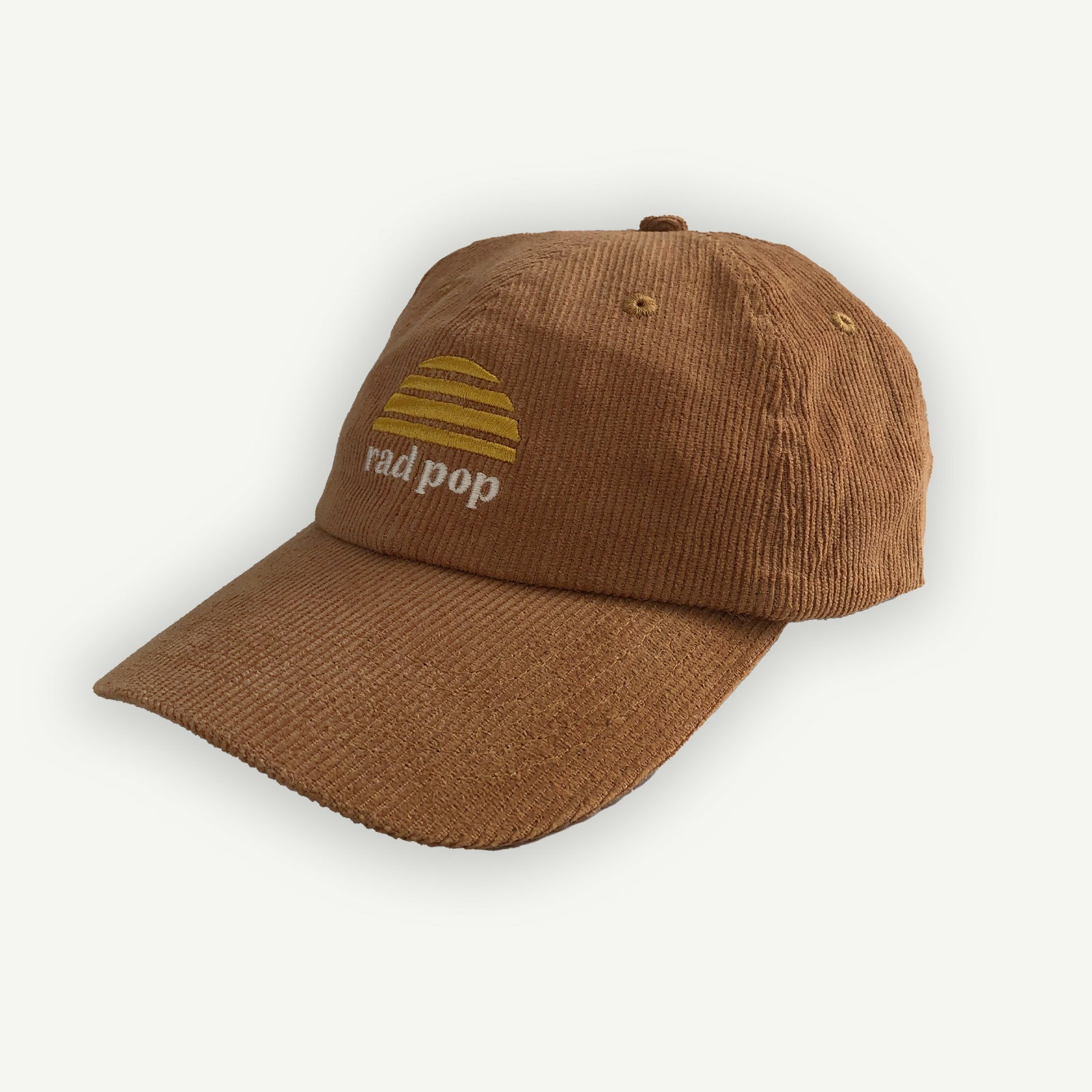 Off center image of Rad pop corduroy flat peaked cap with Banabae sun logo in yellow embroidered on center front with Rad Pop underneath in off white.