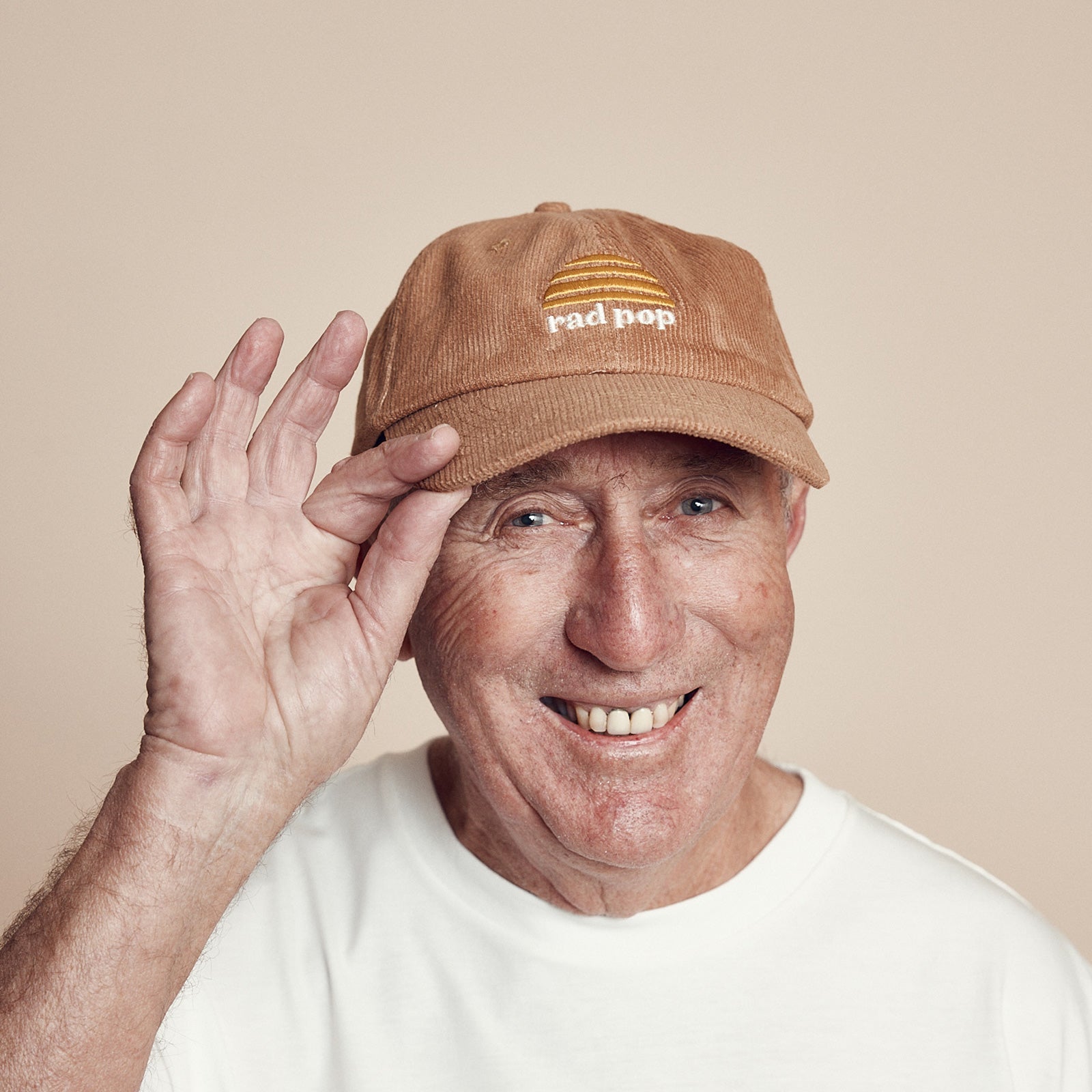 Smiling gentleman wearing the Rad pop corduroy flat peaked cap with Banabae sun logo in yellow embroidered on center front with Rad Pop underneath in off white.