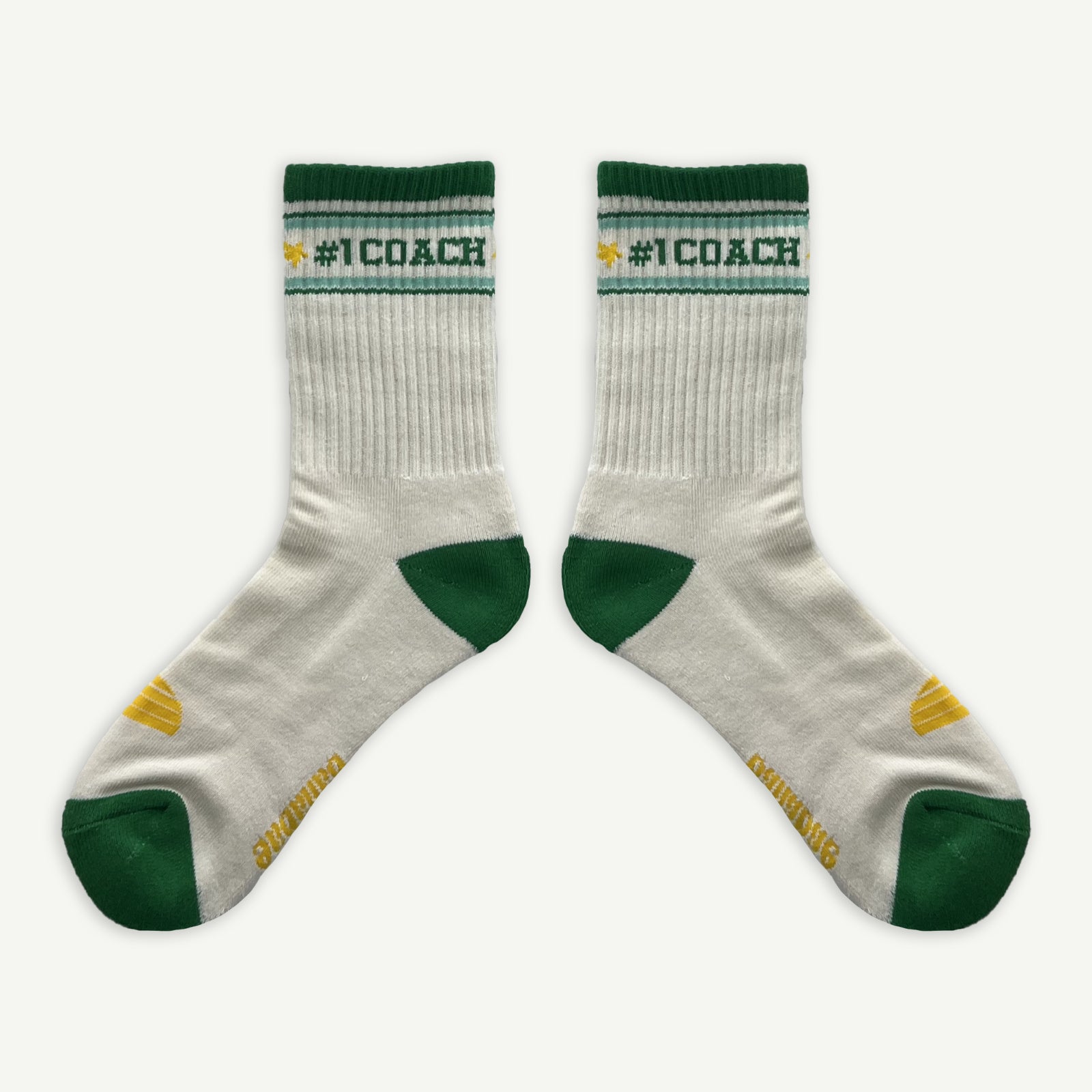 #1 Coach socks, White crew socks with #1 coach in Green written horizontally, bordered with a green and aqua stripe. Toe and heal pads in contrast green with Banabae written along the sole in yellow, and the iconic  Banabae sun logo in yellow placed on top of the foot when worn.