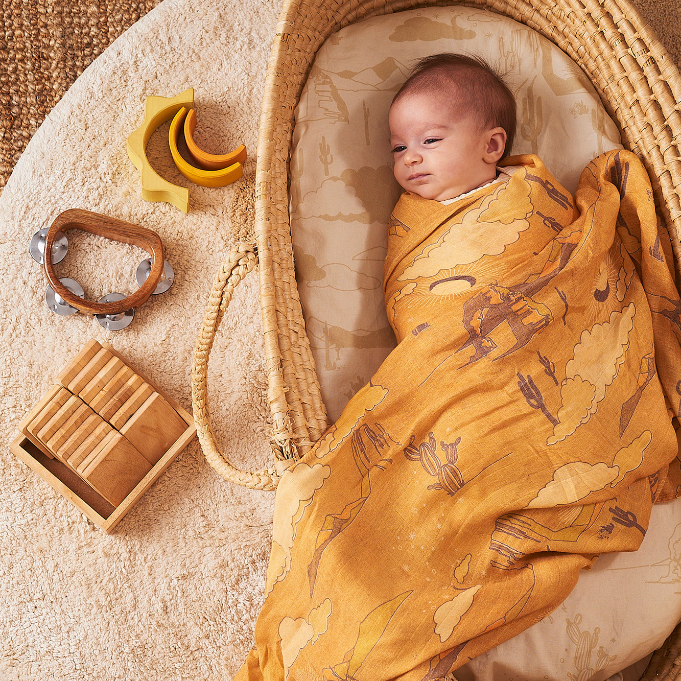 baby wrapped in desert printed swaddle. Print colours are earthy and sand tones